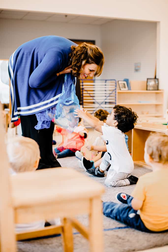 Ms. Amy hands out silks for music time with the toddlers