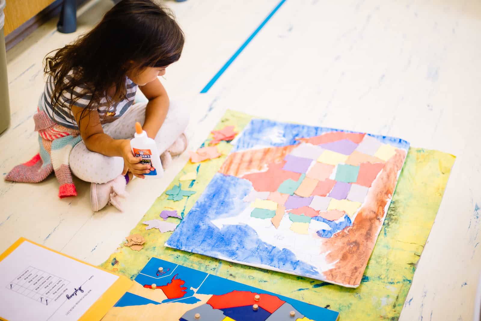 children's house montessori child working on a pin-push map of the united states