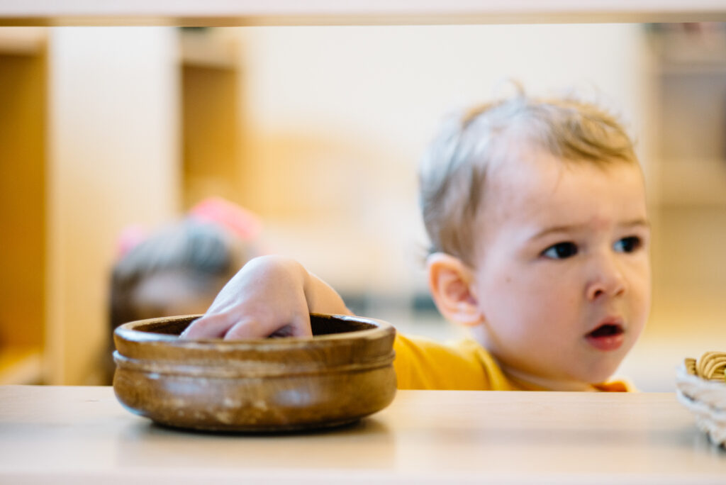 Montessori toddler getting work of the shelf in the classroom