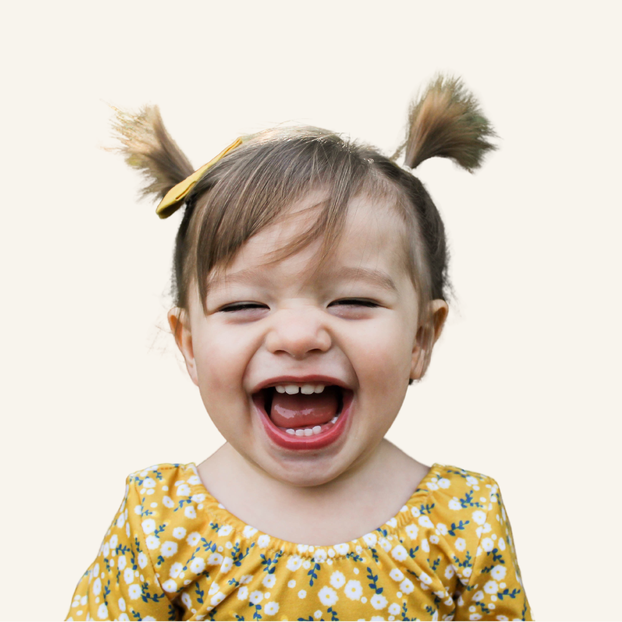A toddler with pigtails laughing.
