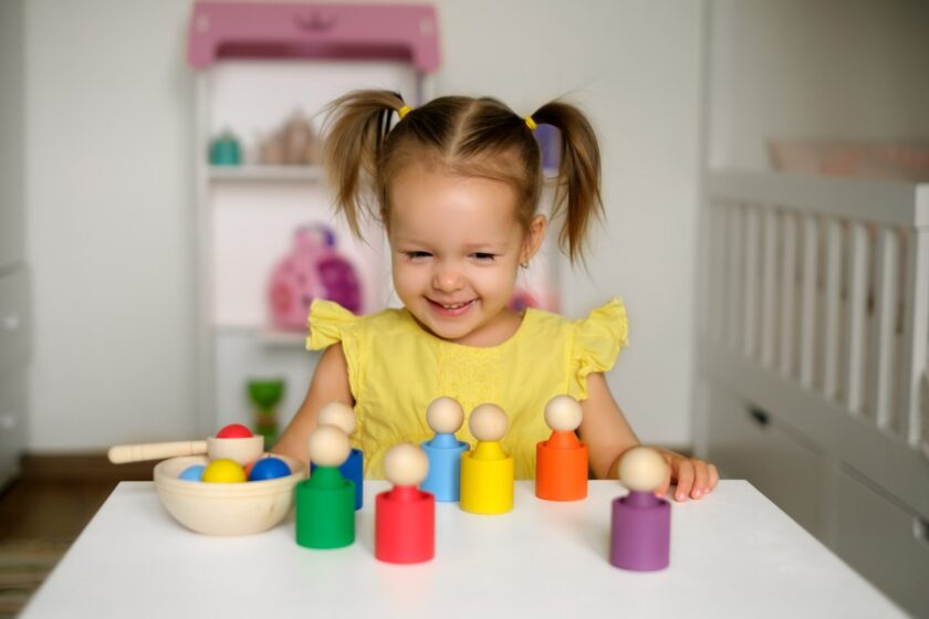 A young girl sitting at a table with toys.