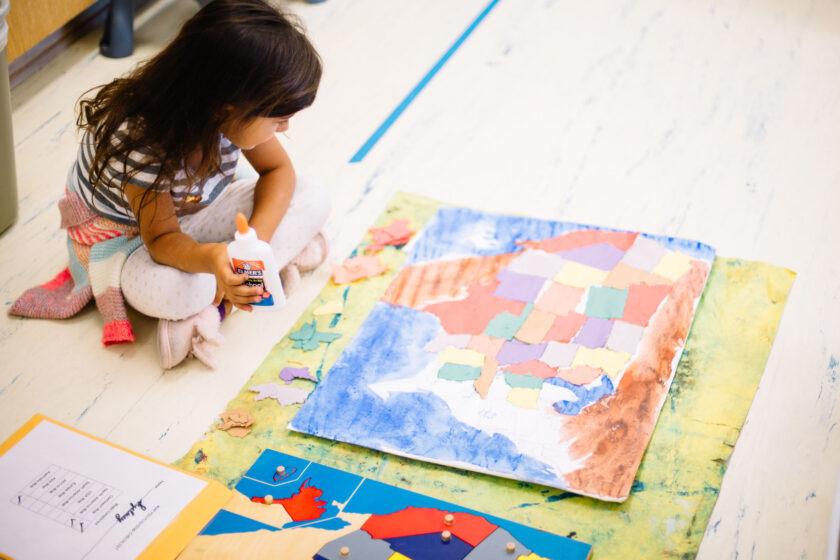 A young student making a map of the United States with colorful construction paper.