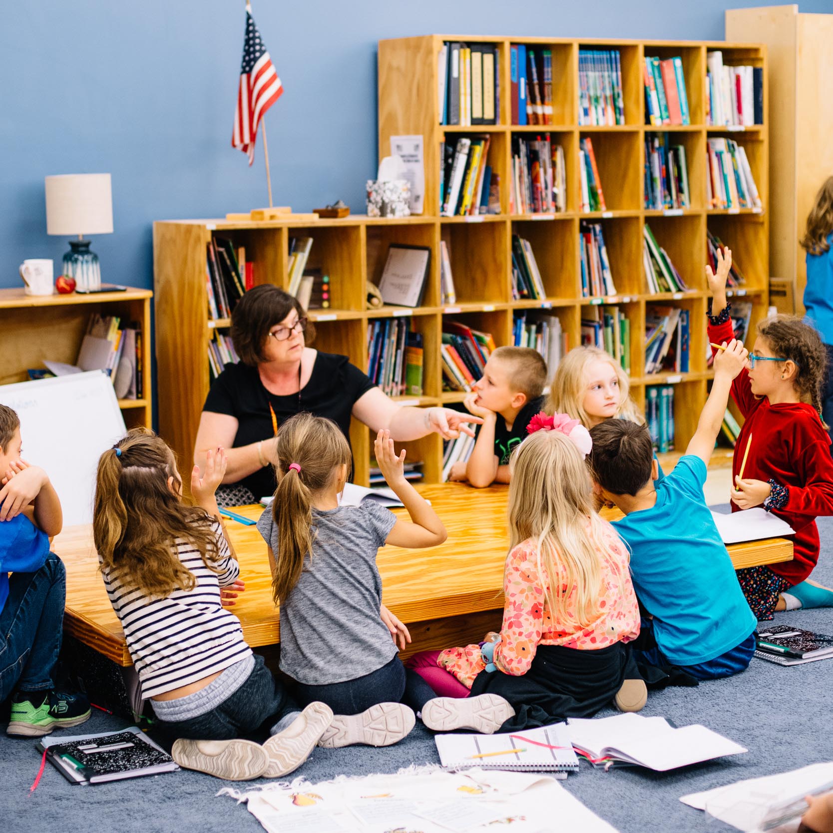 A group of young students sitting at a table with a teacher.