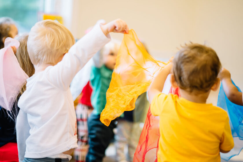 A group of toddlers playing with pieces of colorful cloth.